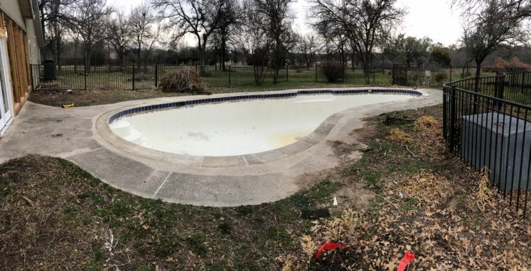 There is a swimming pool in the backyard of a house.