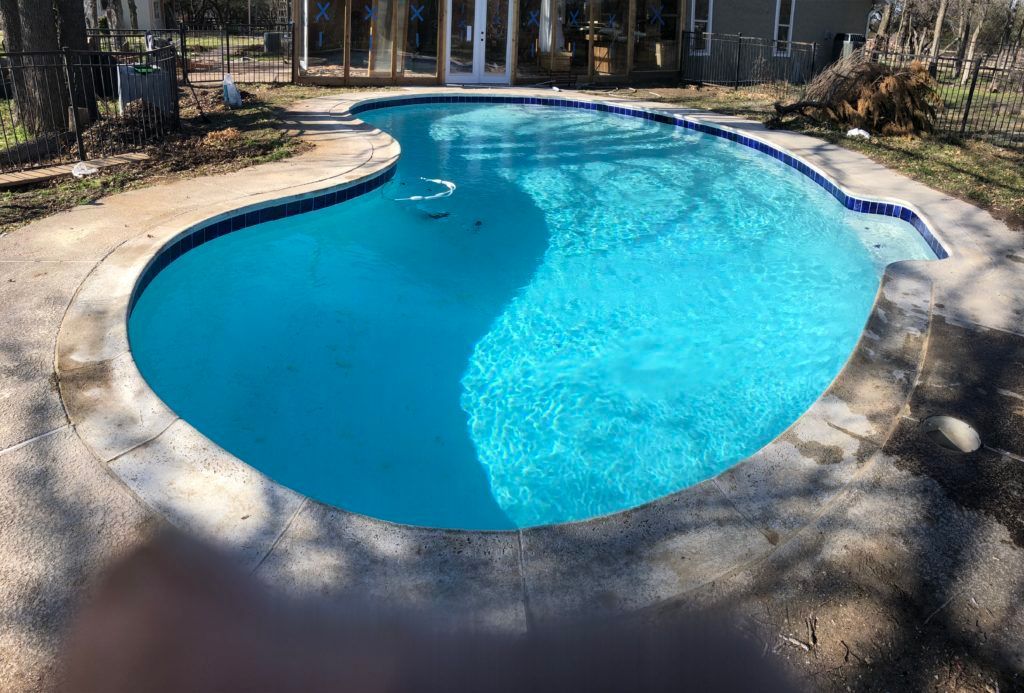 A large swimming pool is sitting in the backyard of a house.