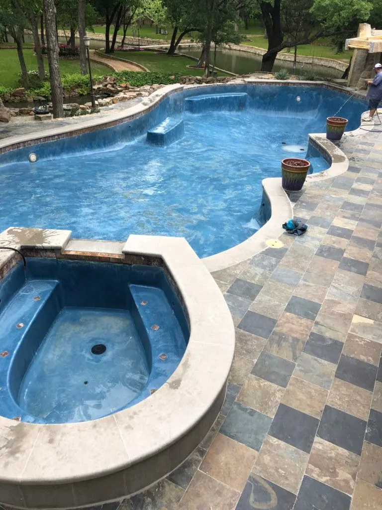 A large swimming pool with a hot tub in the middle of it.