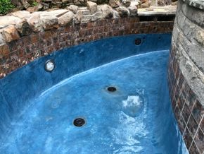 A blue swimming pool surrounded by bricks and rocks.