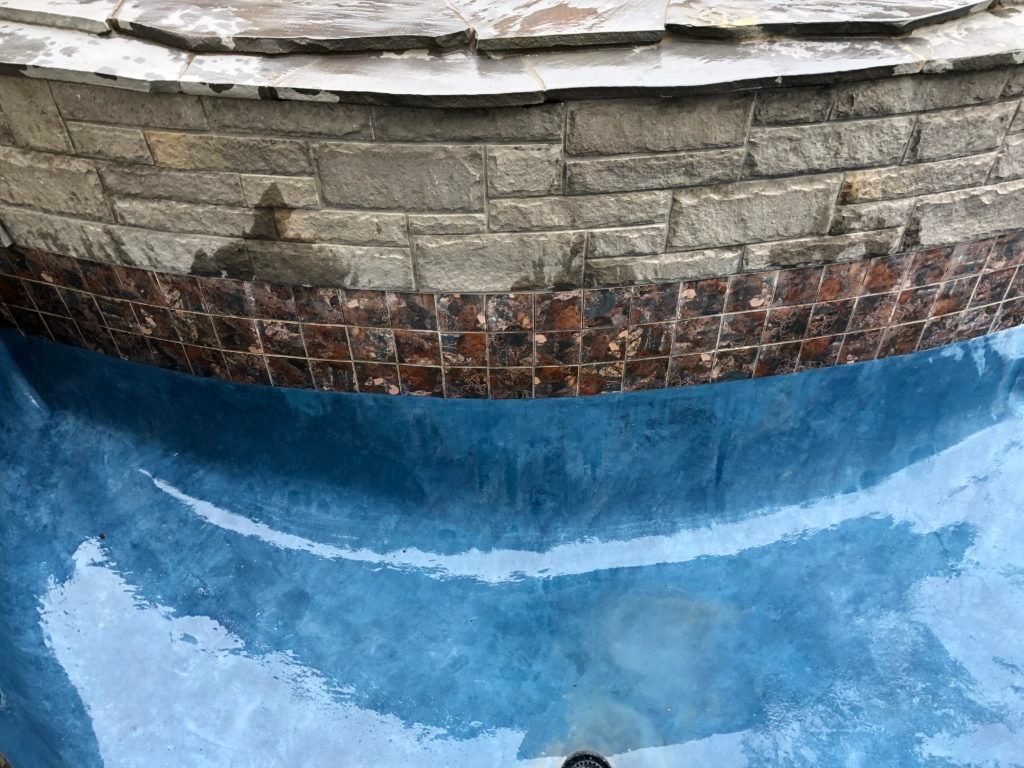 A swimming pool with a brick wall and blue water.