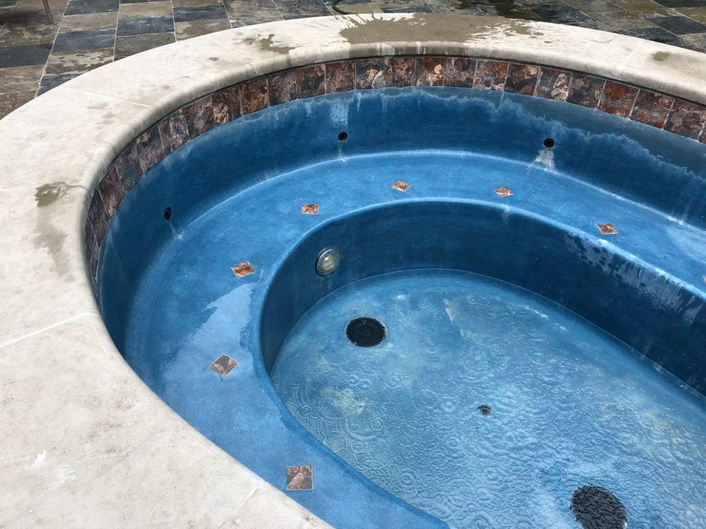 A blue hot tub with a white border and a hole in the middle