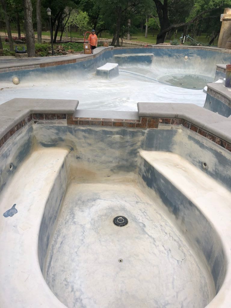 An empty swimming pool with a drain in the middle of it.