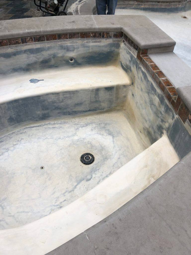 A person is standing next to a swimming pool that is being remodeled.