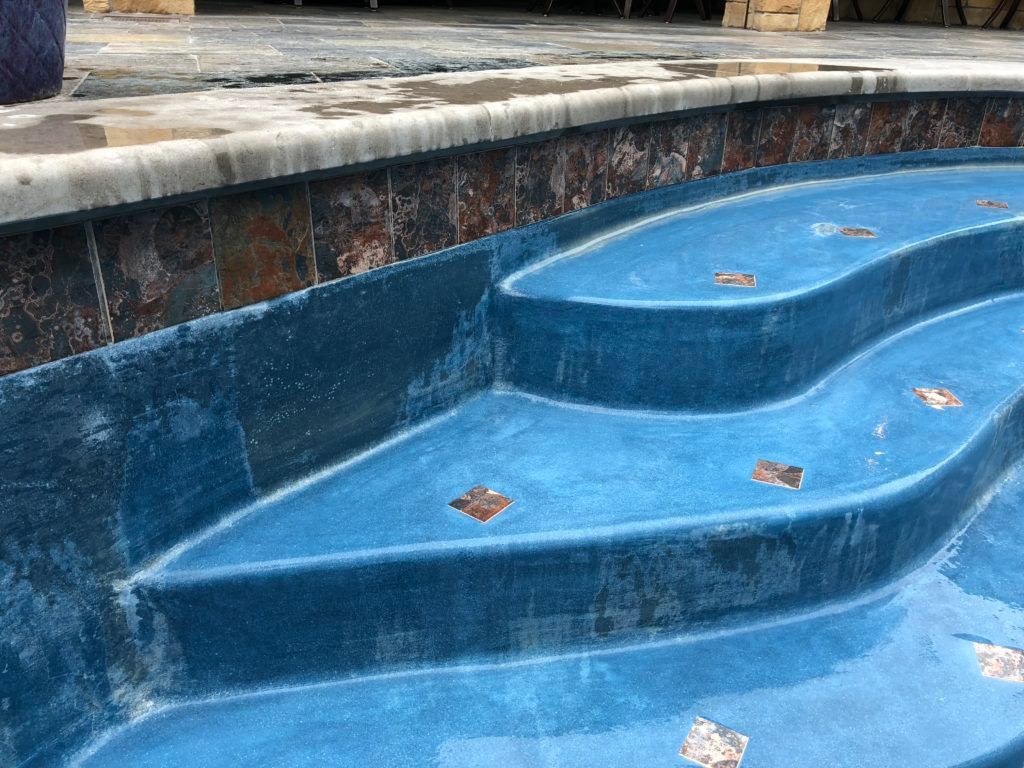 A blue swimming pool with stairs leading up to it.