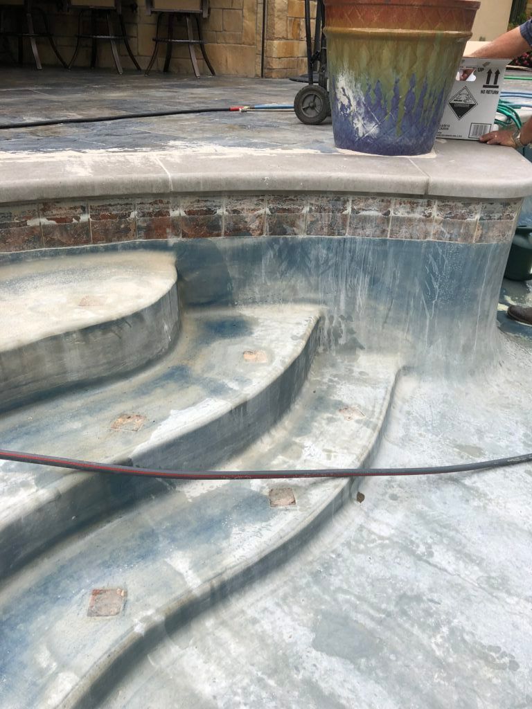 A person is cleaning a swimming pool with a hose.