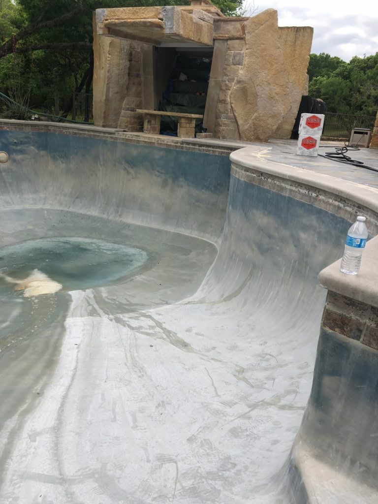 A bottle of water is sitting on the edge of a pool.