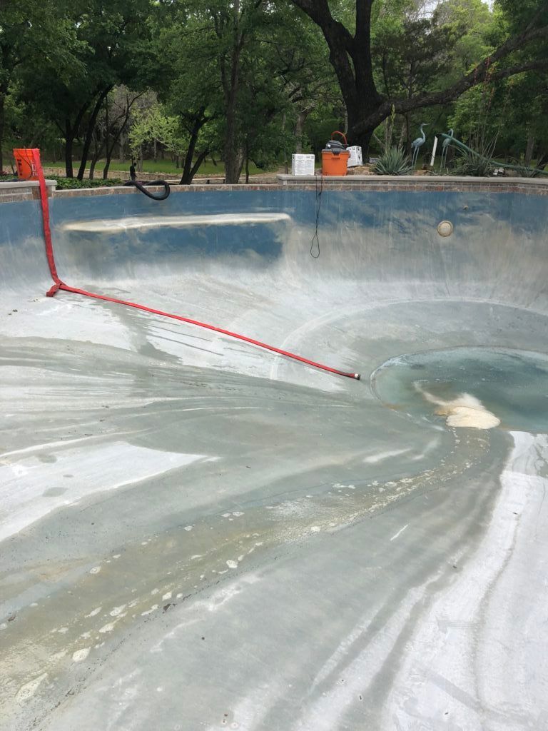 An empty swimming pool with a red pole in the middle of it.