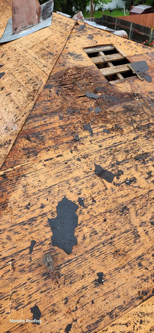 A weathered, brown roof with missing shingles, visible wood, and a chimney.