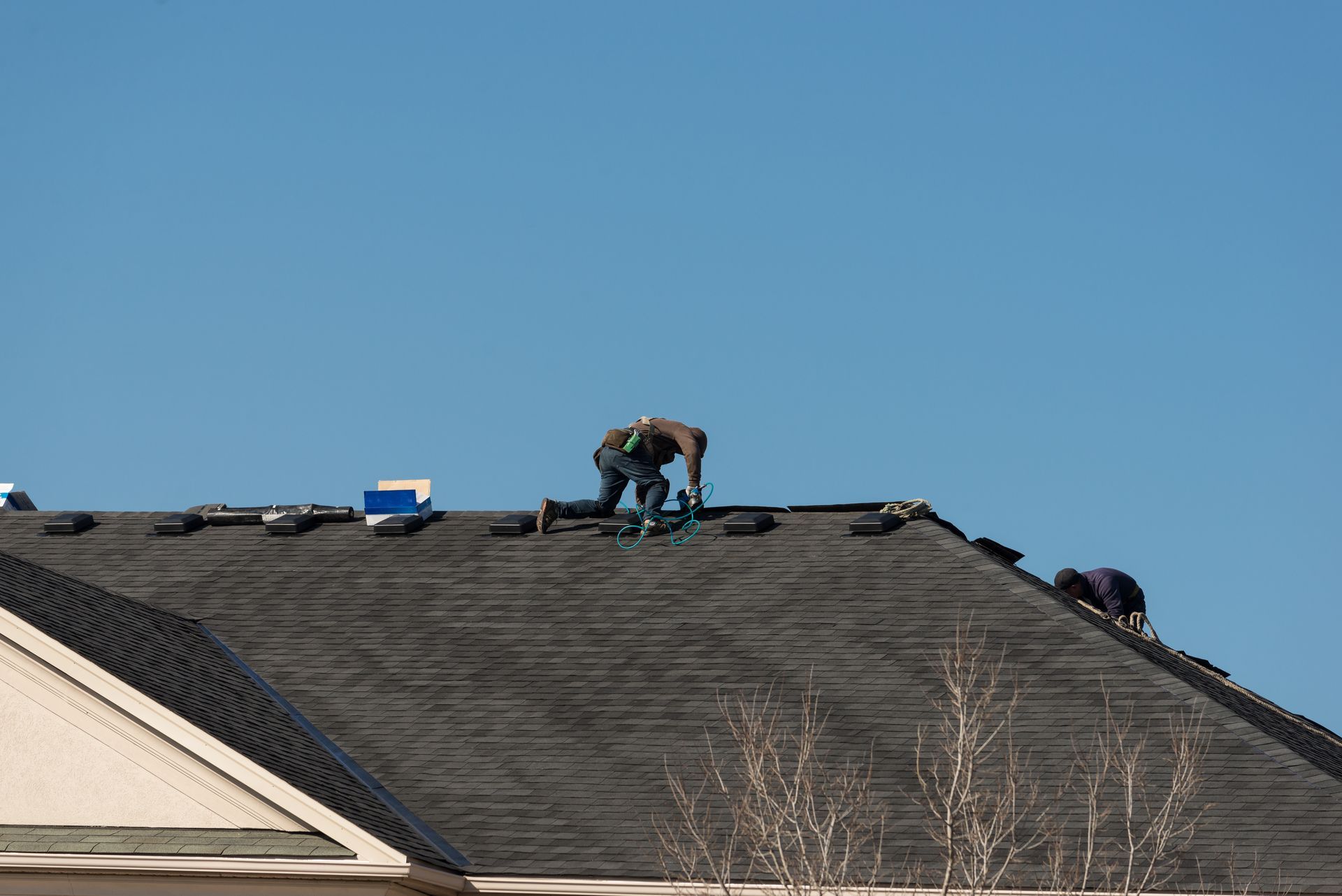 Emergency roofer repairing a roof with new shingles.