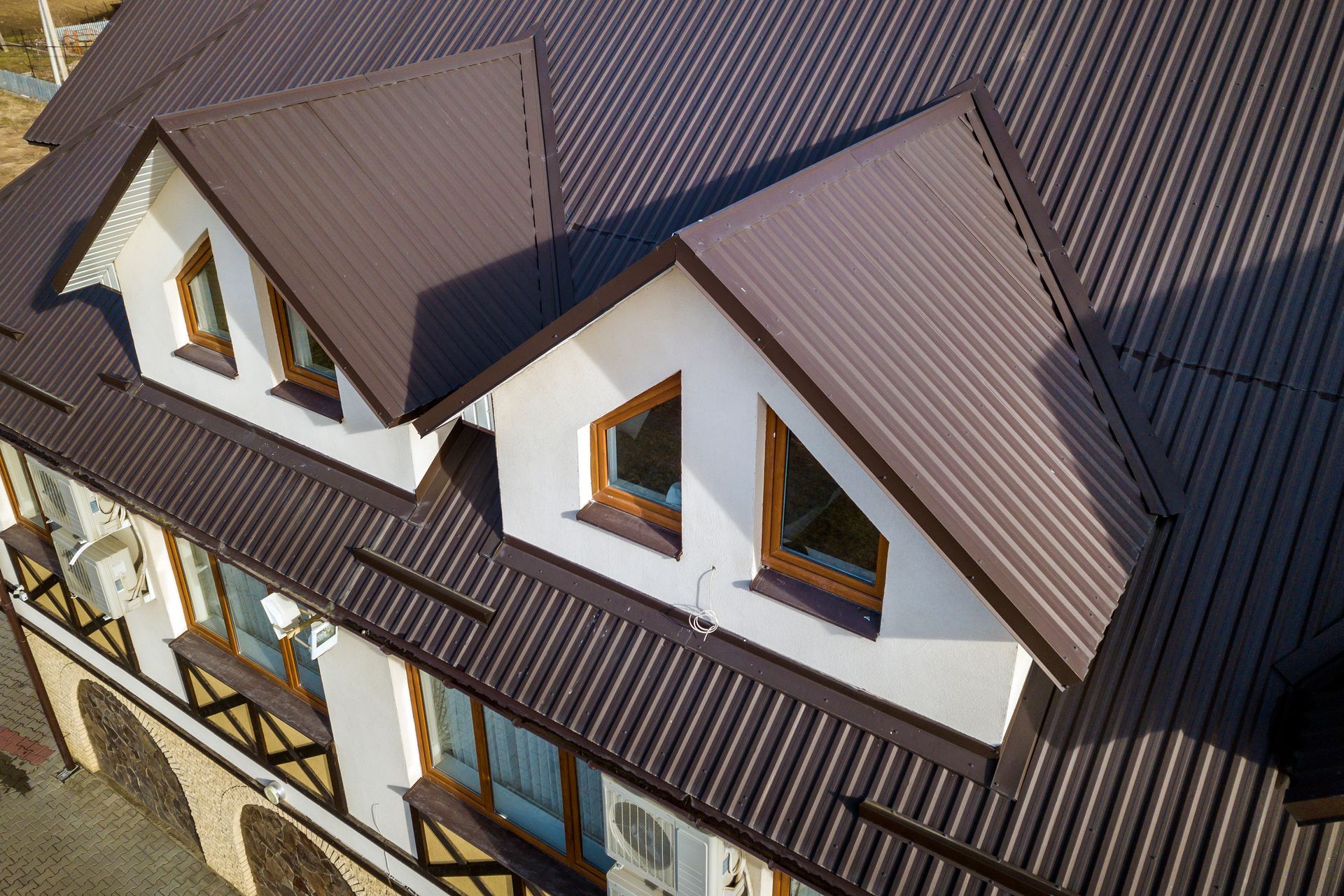 Brown metal roof with three dormers, white walls, and brown trim.