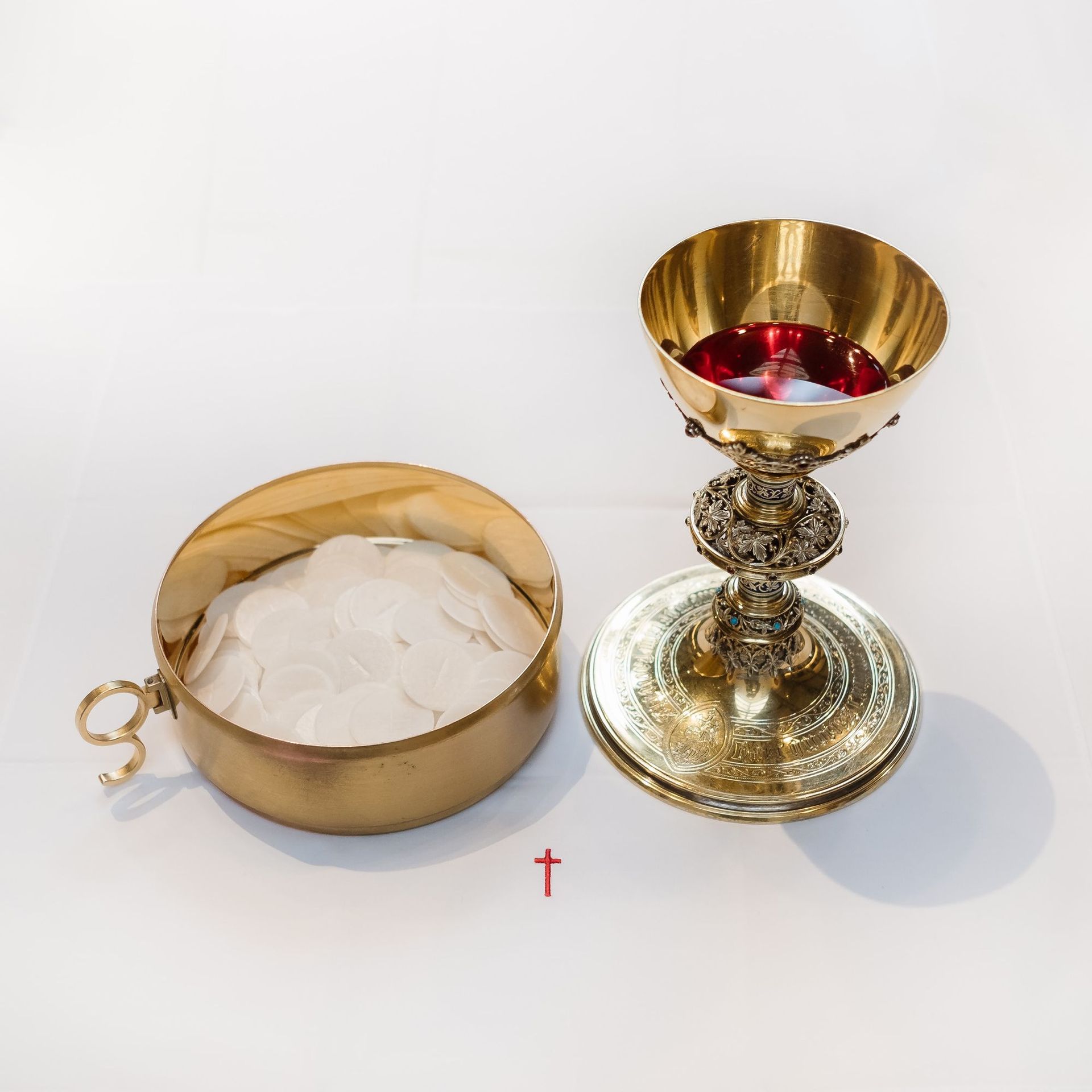 A chalice with red wine and bread next to a cross
