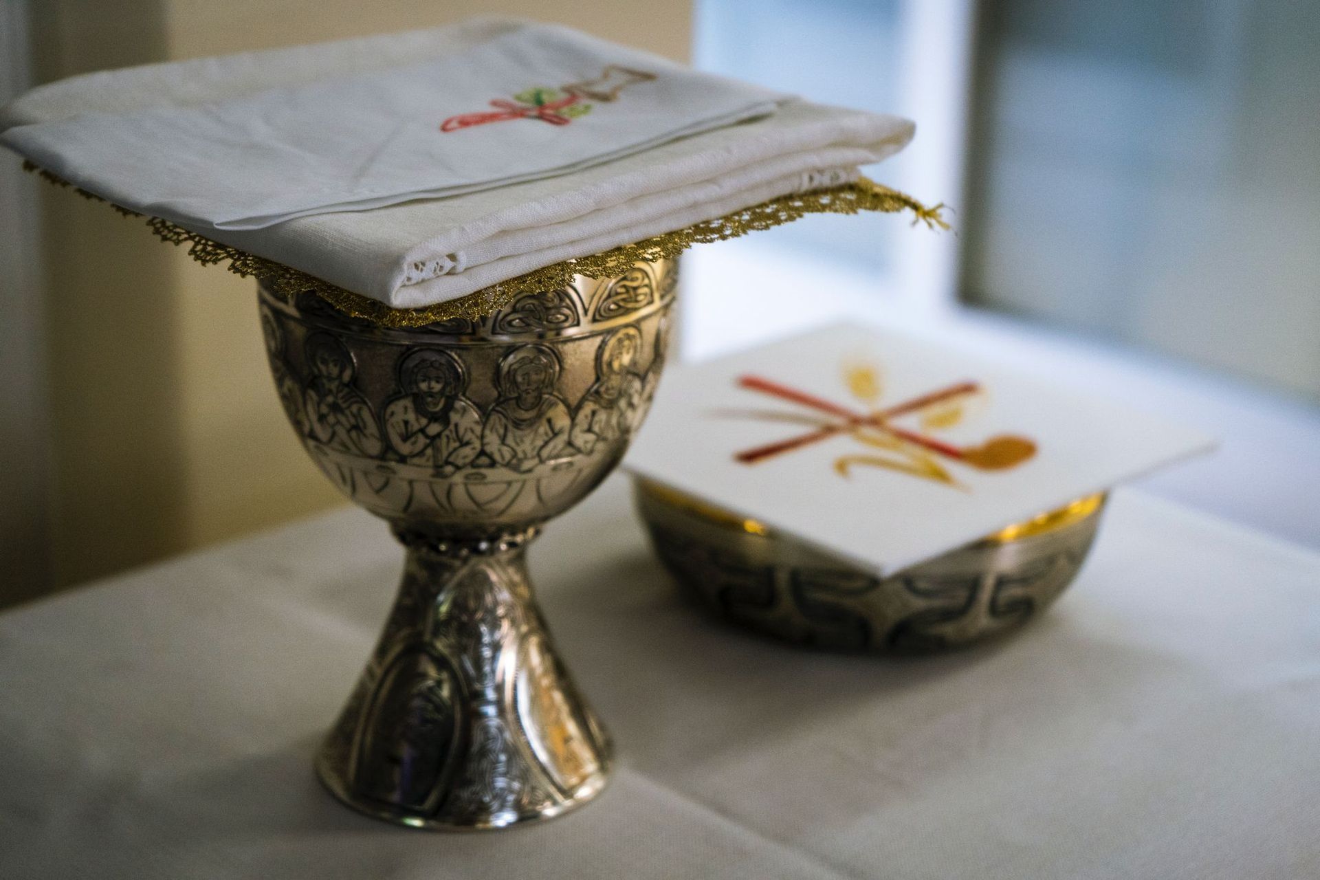 A chalice with a cloth on top of it and a bowl on a table.