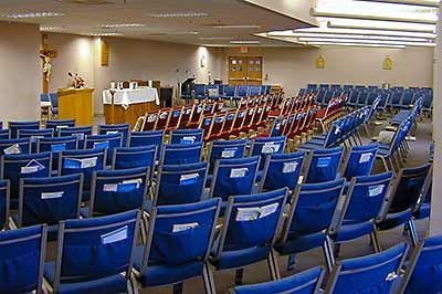 Rows of blue chairs in a large room with a podium in the background