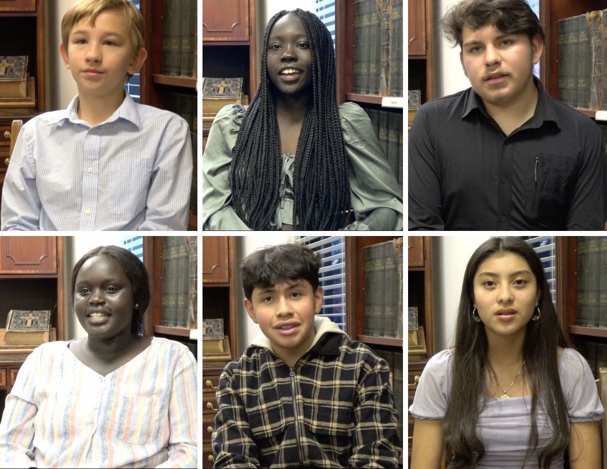 Six students in a library setting, facing the camera and smiling.