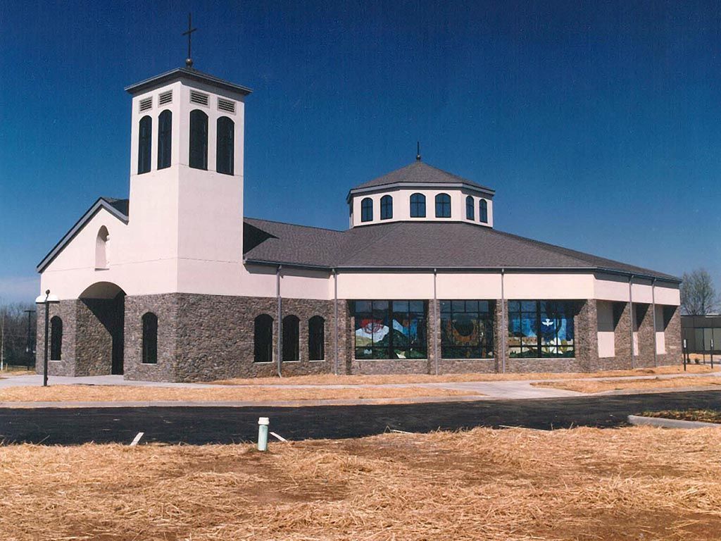 A white building with a gray roof and a cross on top