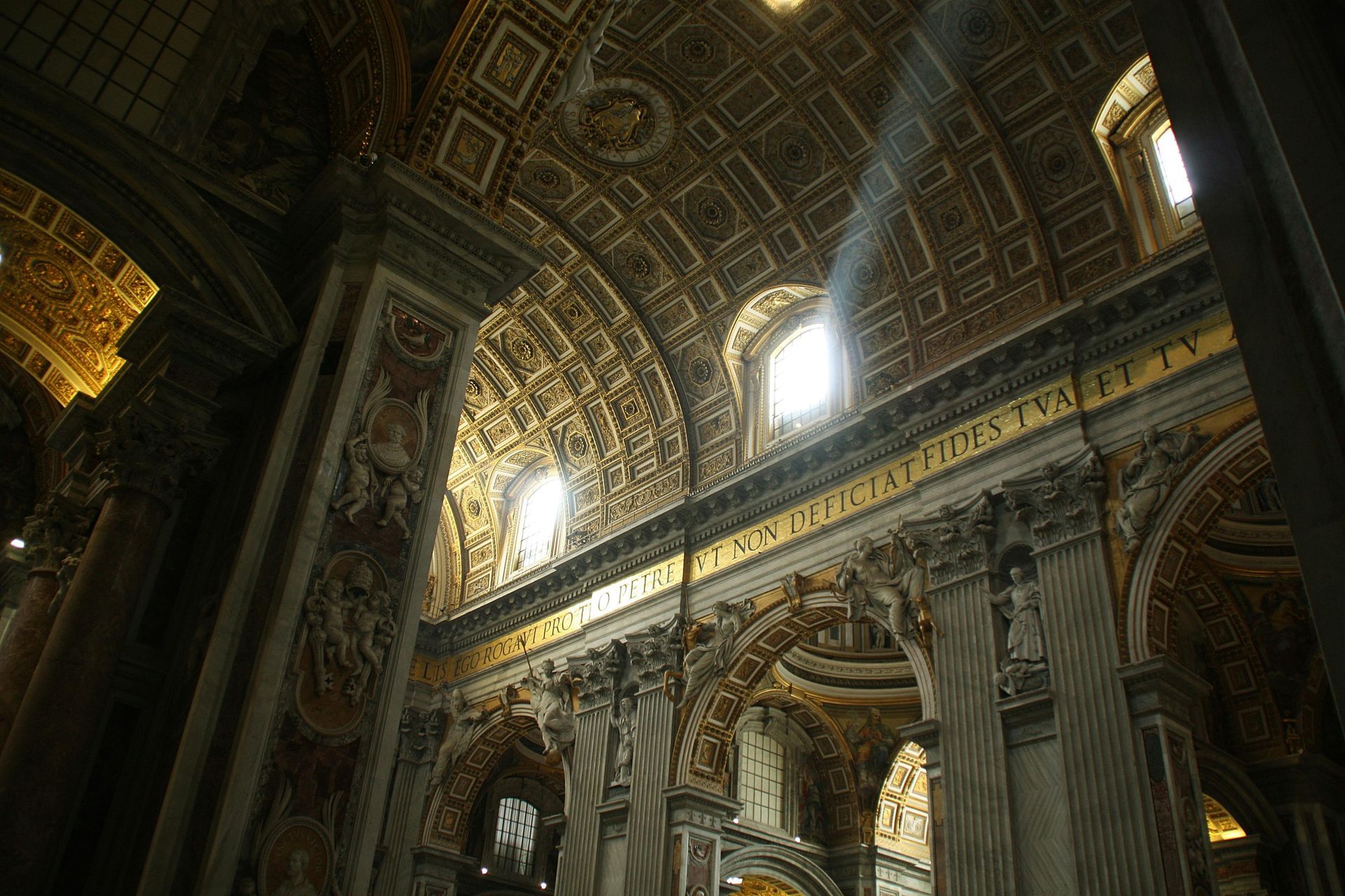 Looking up at the ceiling of a church with the sun shining through the windows.