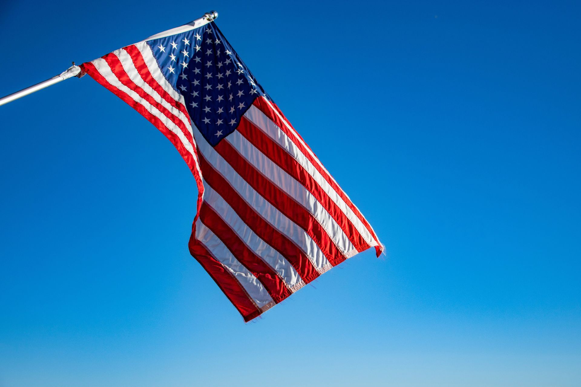 American flag waving against a clear blue sky
