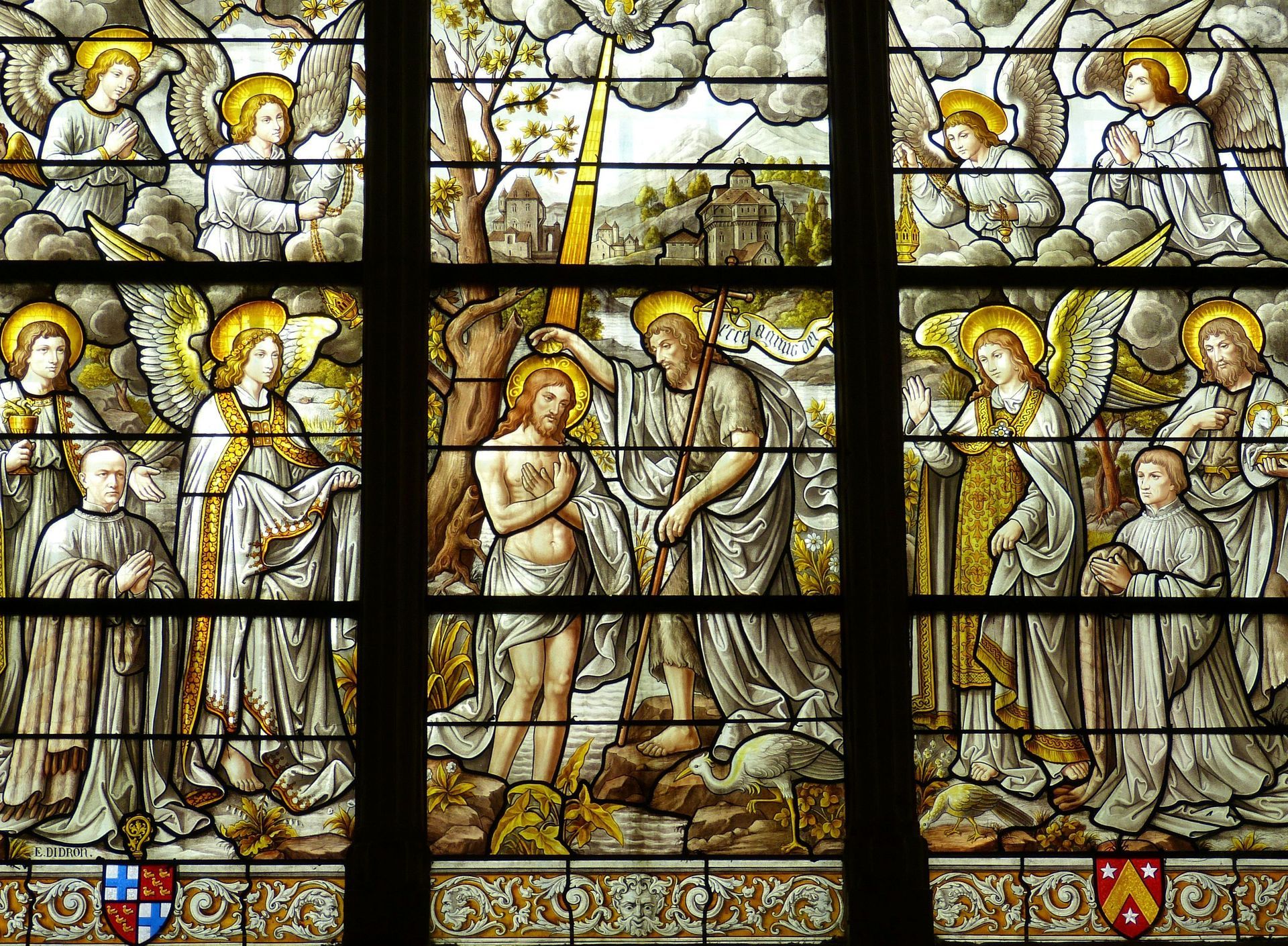 A stained glass window in a church depicting the baptism of jesus.