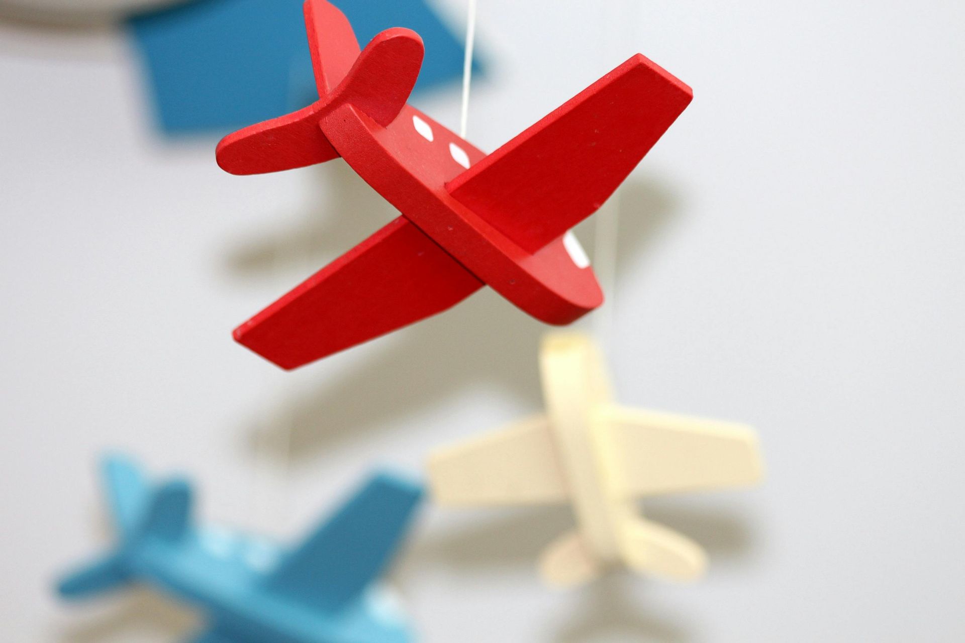 Red, blue, and yellow wooden toy airplanes hanging from a string.
