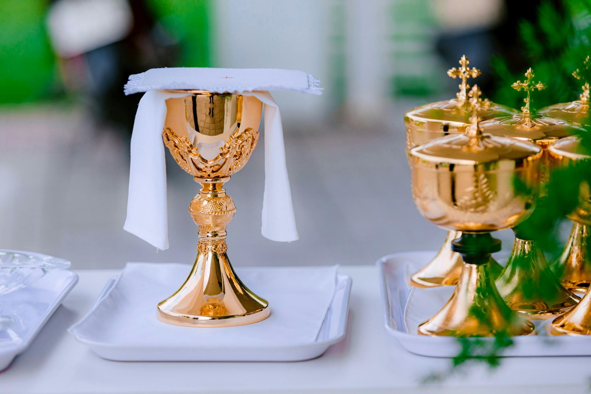 A group of gold chalices sitting on top of a white tray on a table.