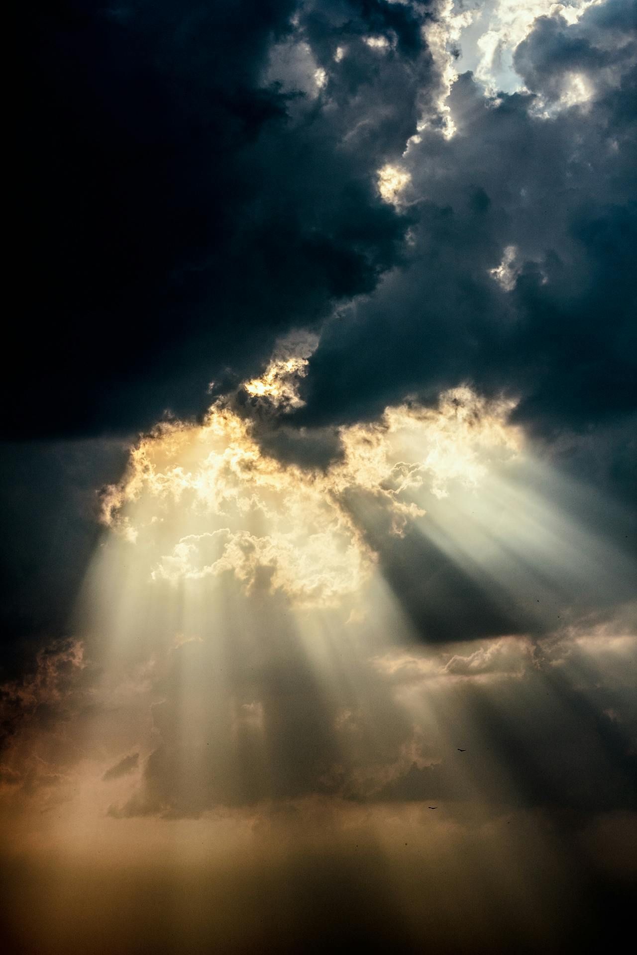 The sun is shining through the clouds in the sky.