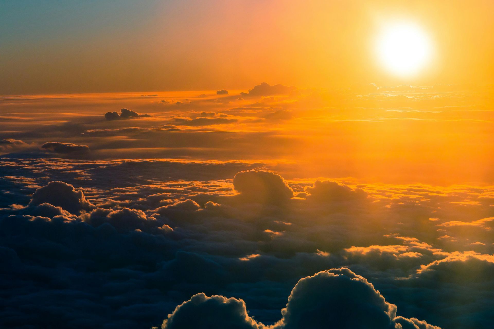Golden sunset over a sea of clouds, with the sun's bright light shining through the atmosphere.