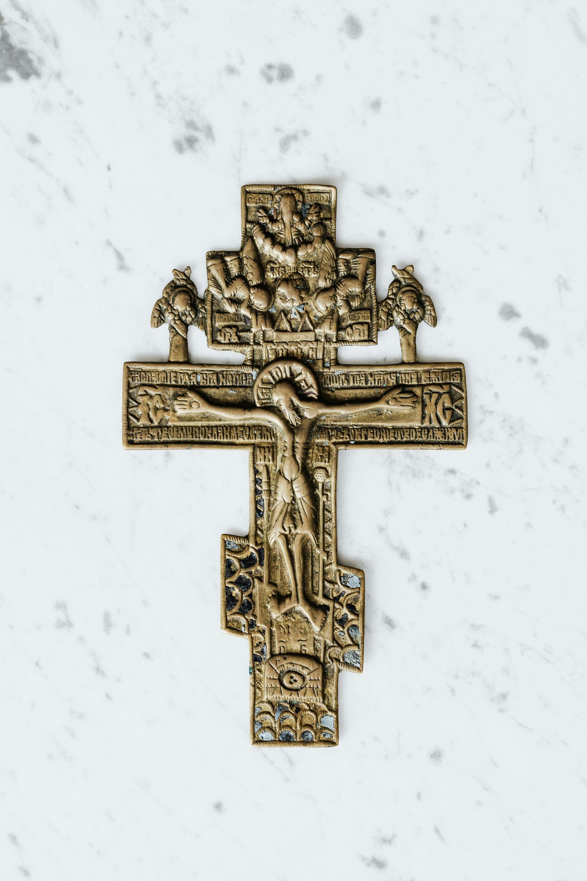 A cross with jesus on it is on a white surface.