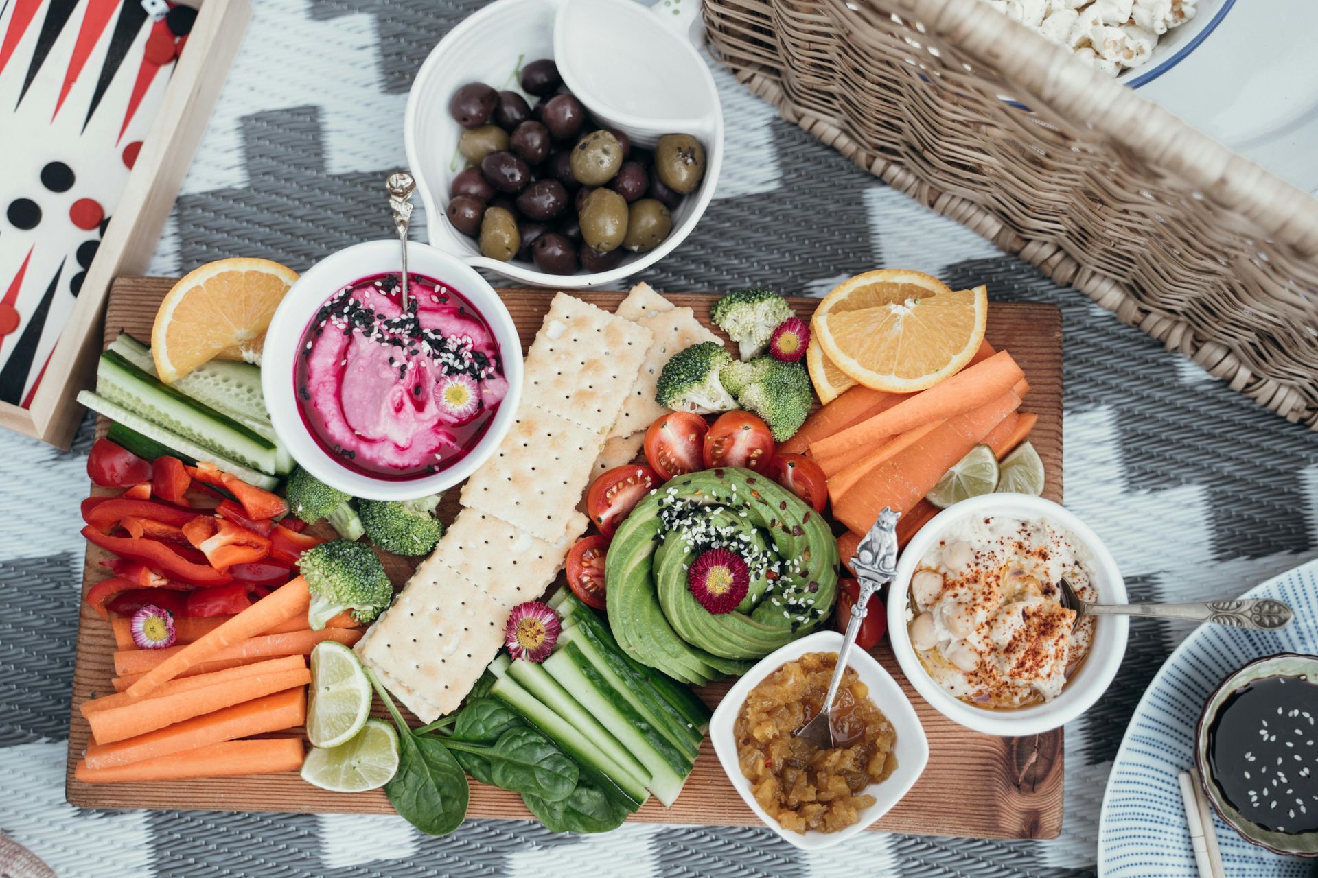 A wooden cutting board topped with a variety of vegetables and dips.