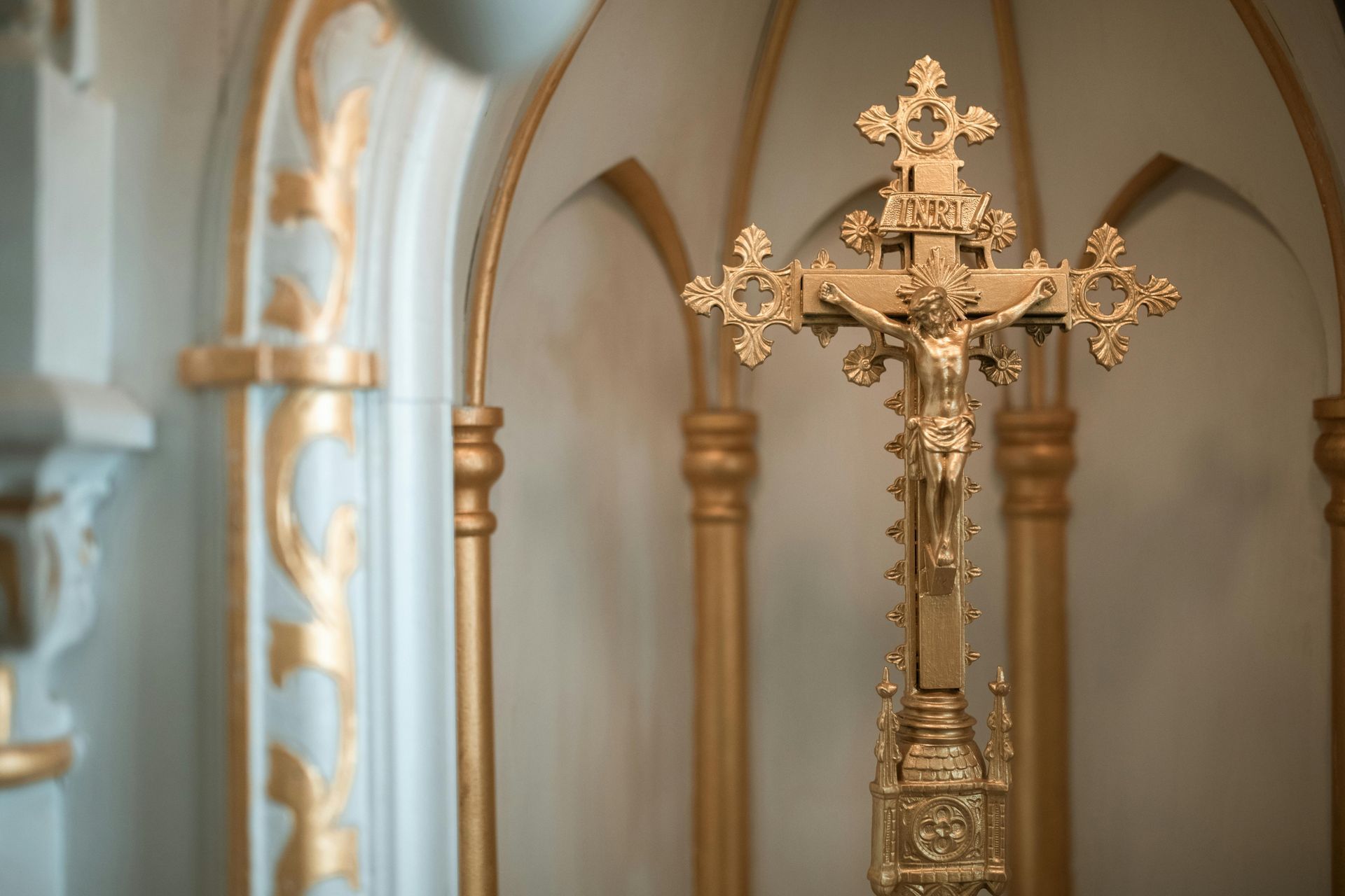 A gold cross with jesus on it is in a church.