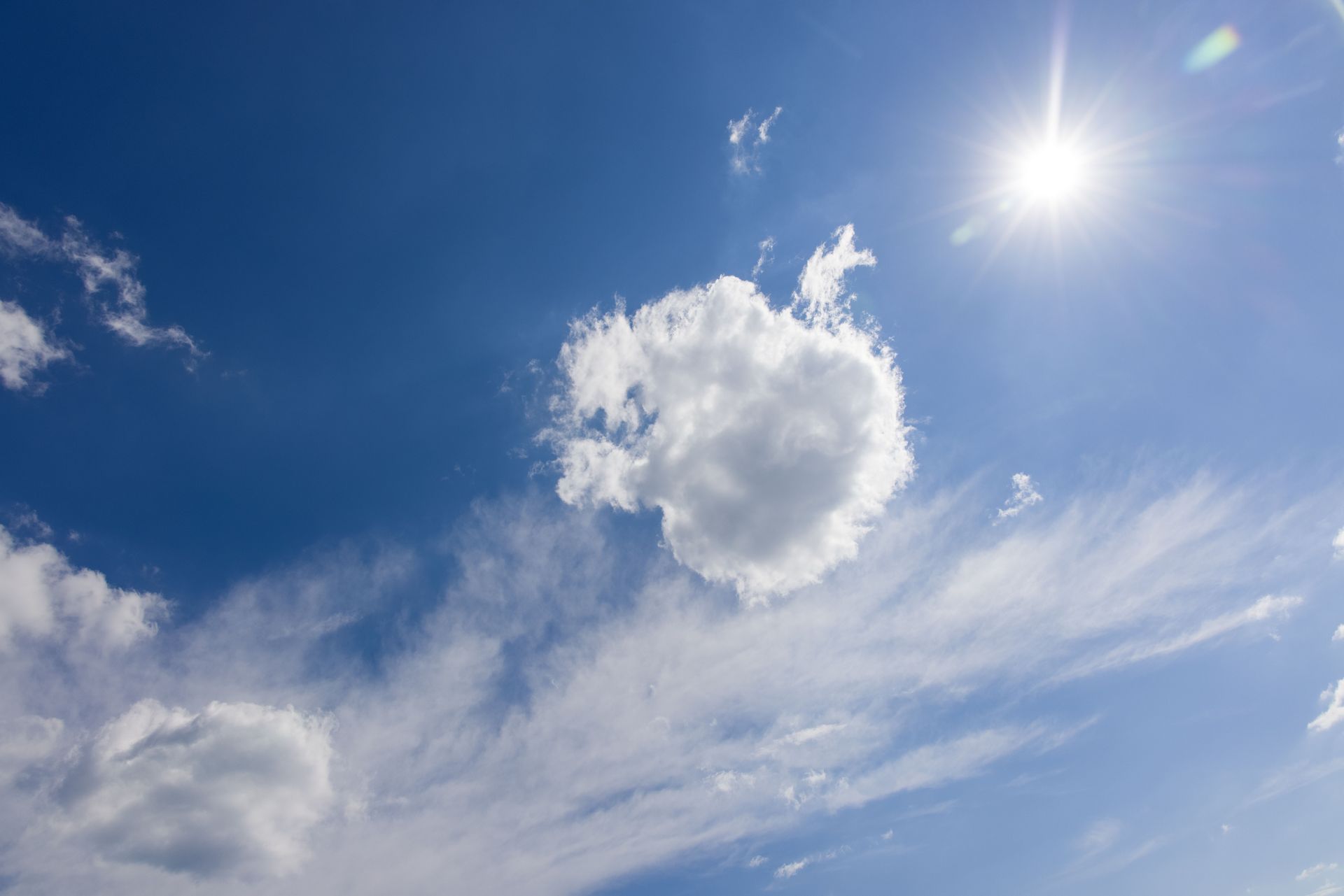 Blue sky with wispy clouds and a bright sun in the upper right
