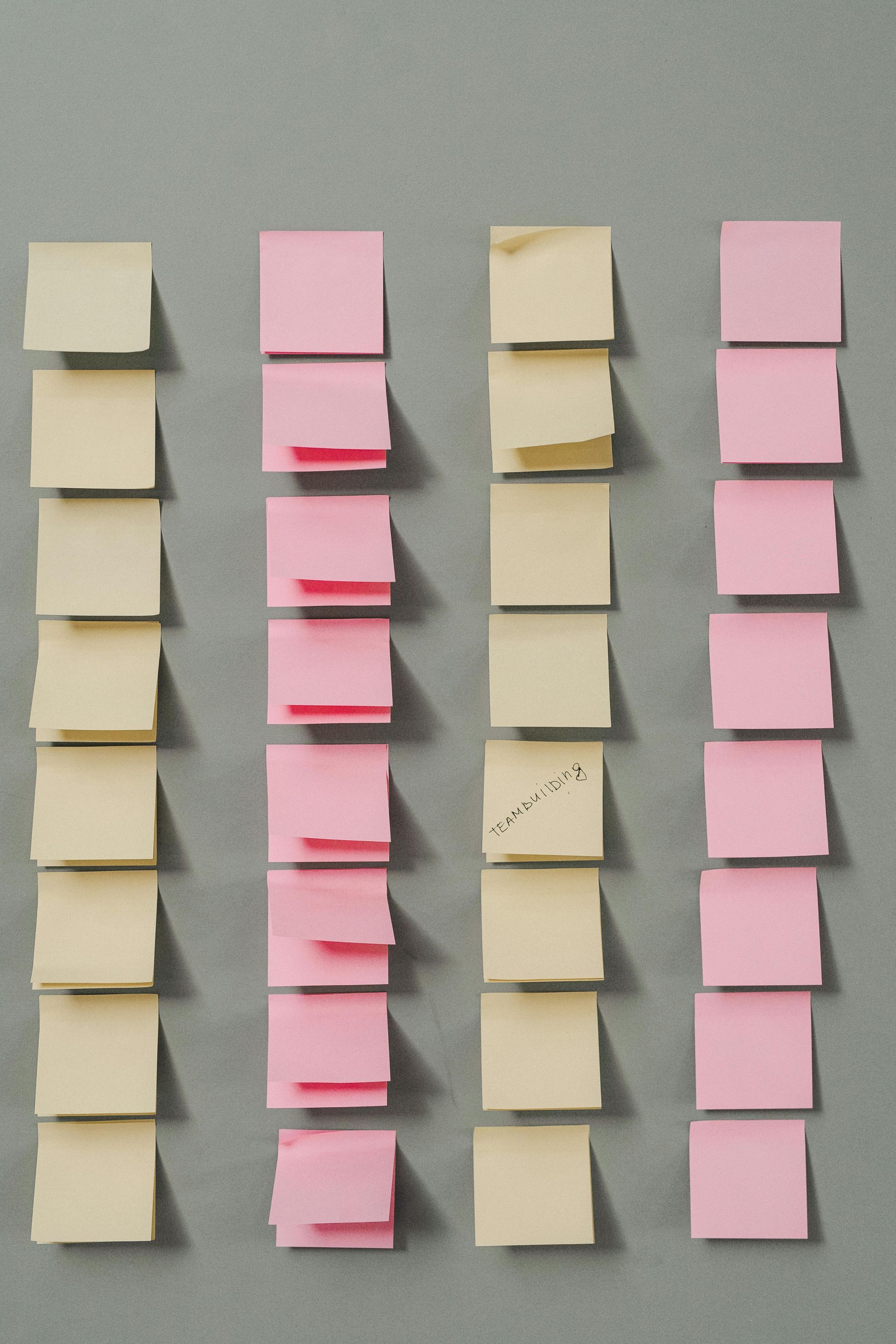 A row of pink and yellow sticky notes on a wall