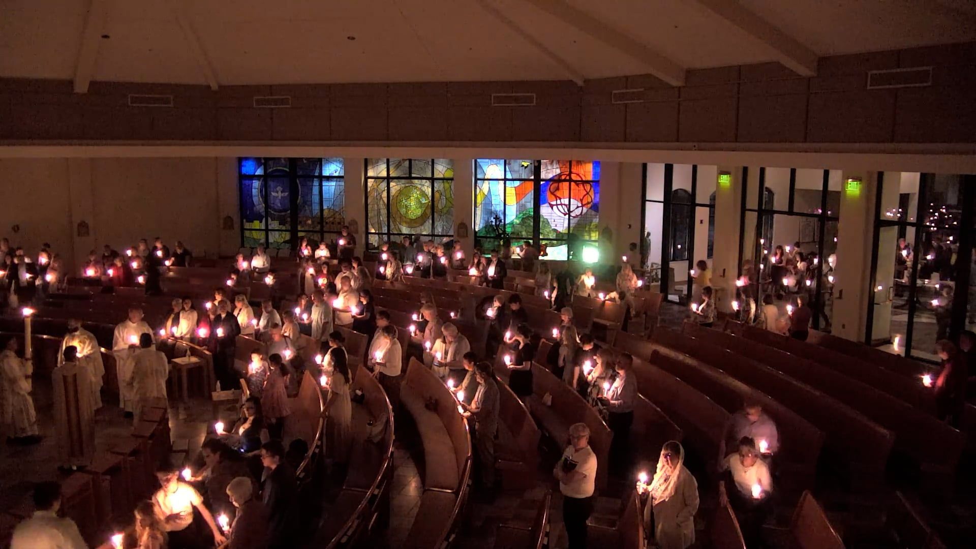 Picture of Parishioners at Easter vigil holding candles walking into Our Lady of Fatima Church. 