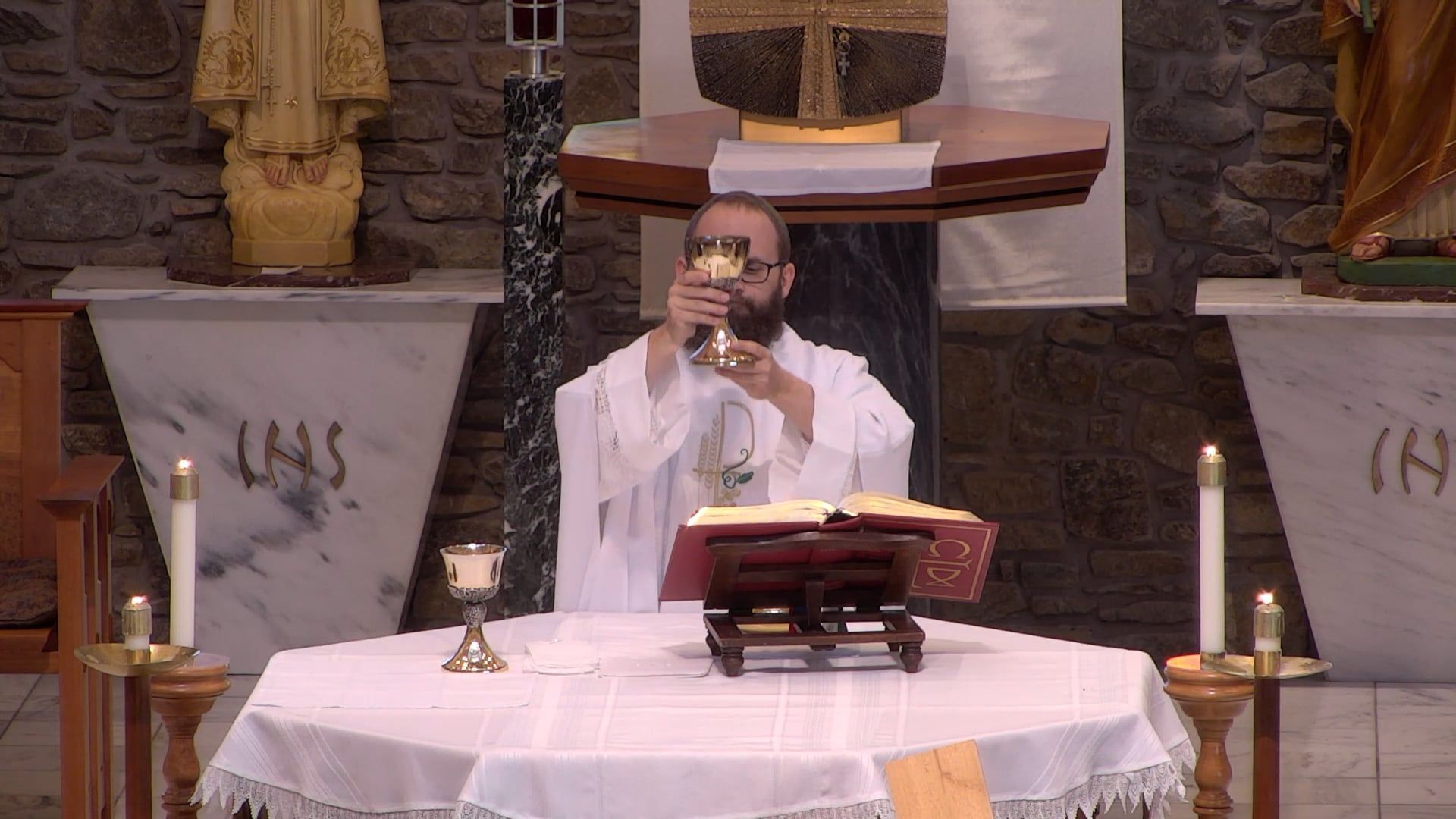 Fr. Joe is holding a chalice up in the air at the altar in the main church