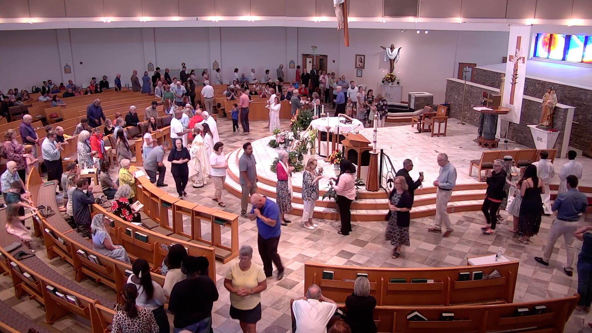 A large group of people are gathered in a church receiving the eucharist. 