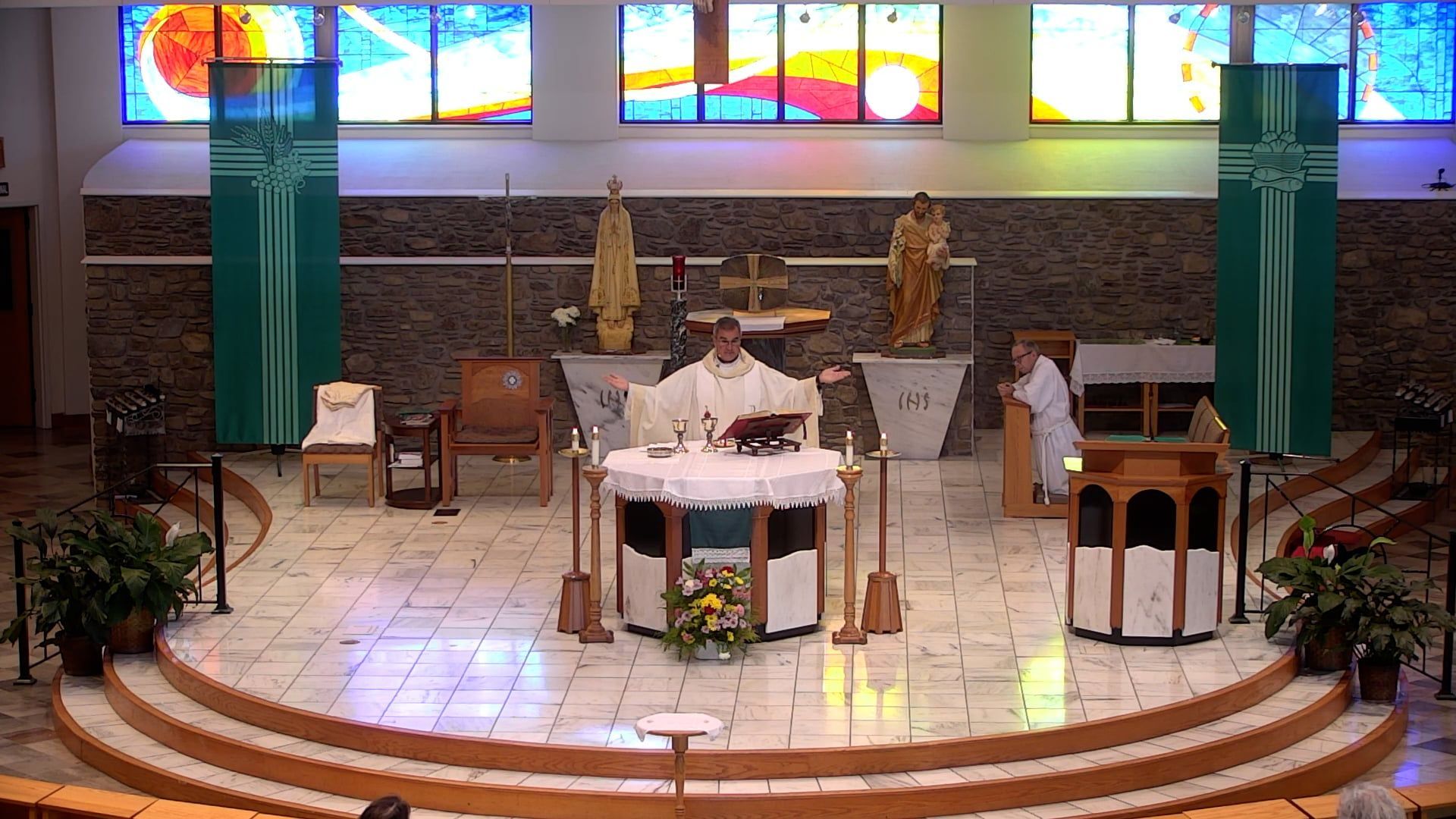 Fr. Pete at the main church at the altar with hands raised. 