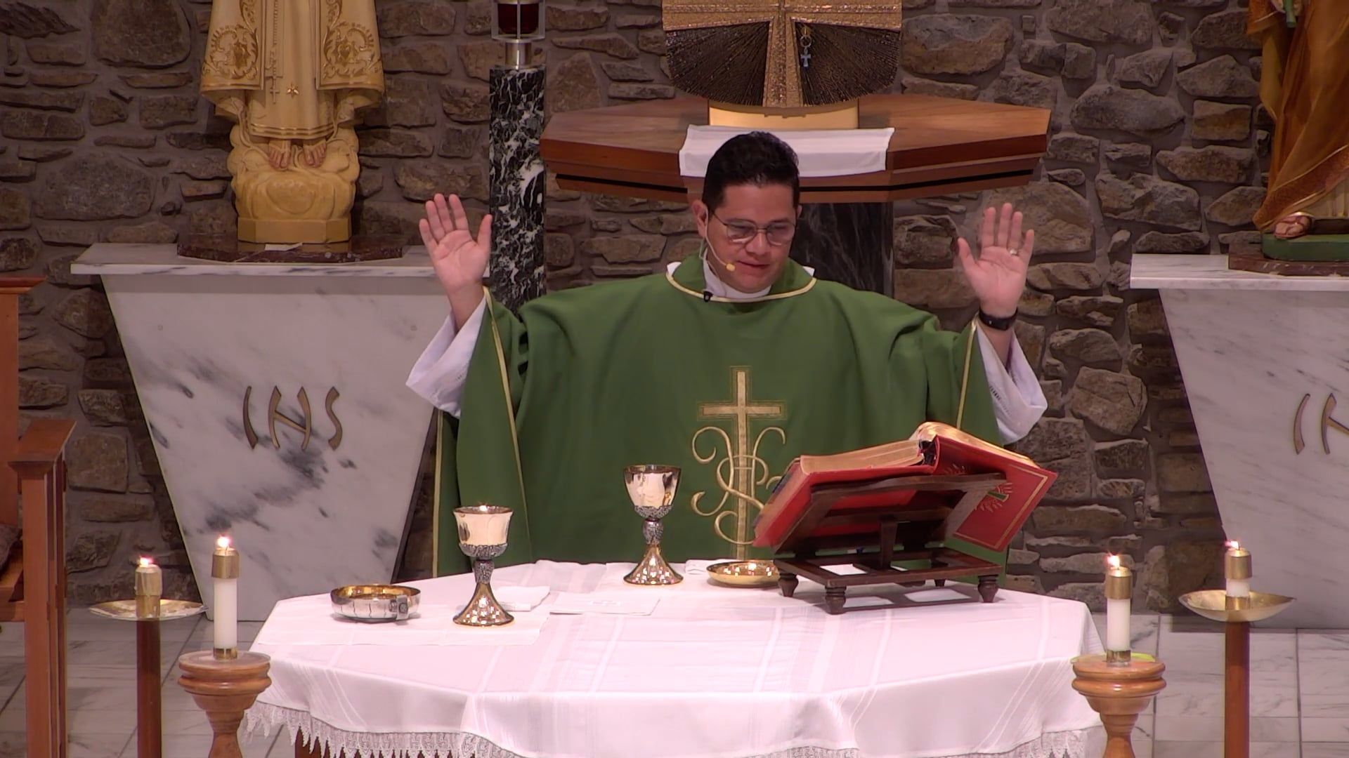 Fr. Renzo with his arms raised at the altar celebrating mass in the main church. 