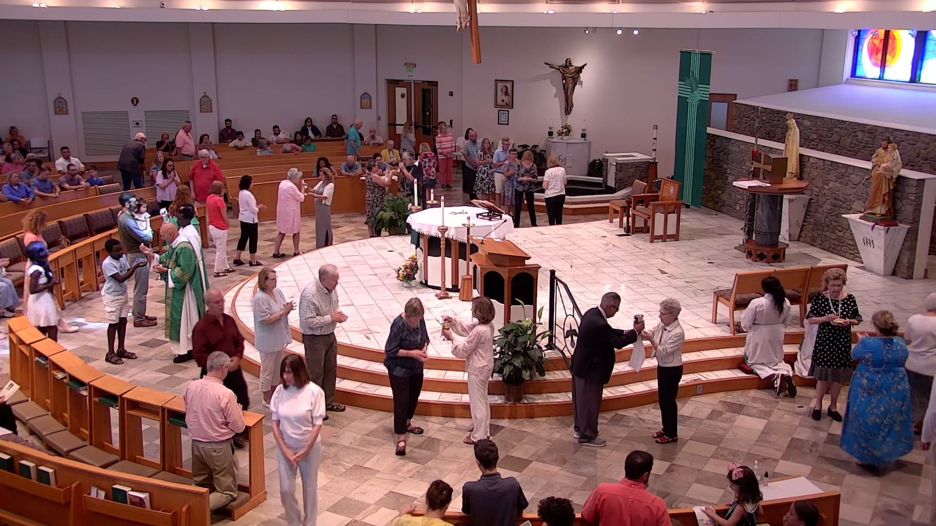 A large group of people are gathered in a church receiving communion. 