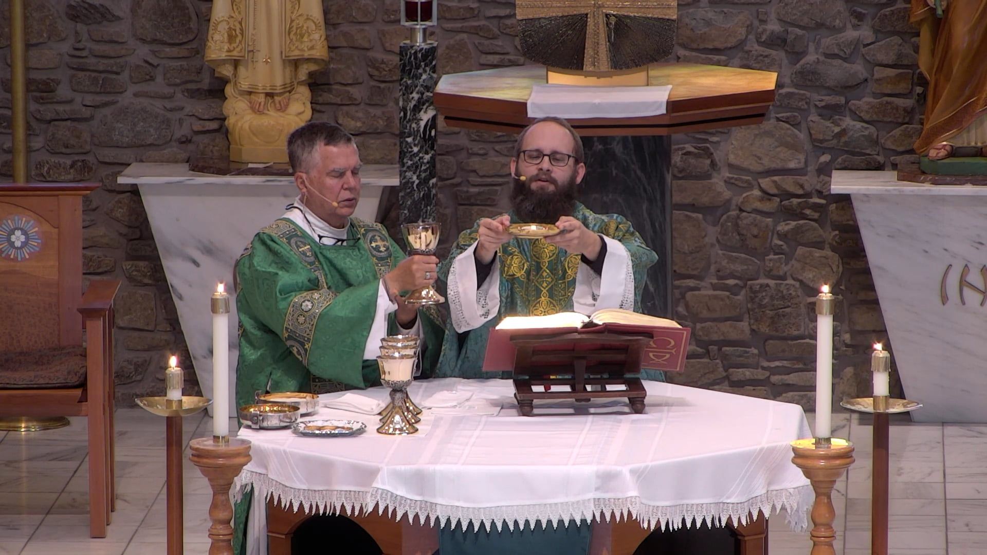 Father Joe  with Deacon Leon holding the chalice celebrating mass at the altar tin the main church. 