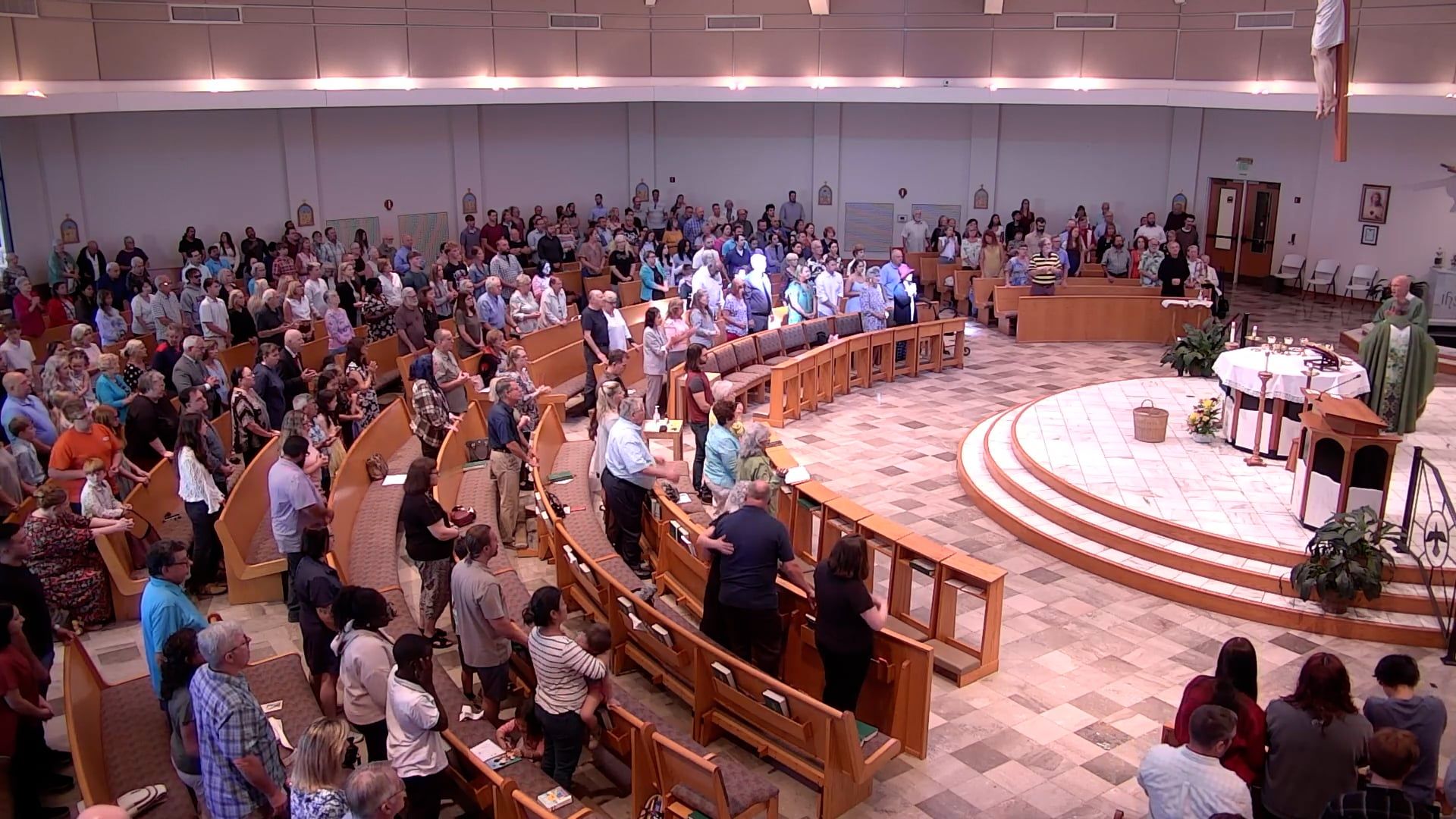 People in a church, standing and seated during a service. The altar is at the front.