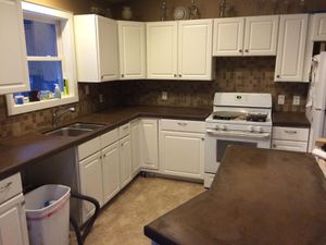 Small kitchen with white cabinets, dark countertops, a gas stove, and a window over the sink.