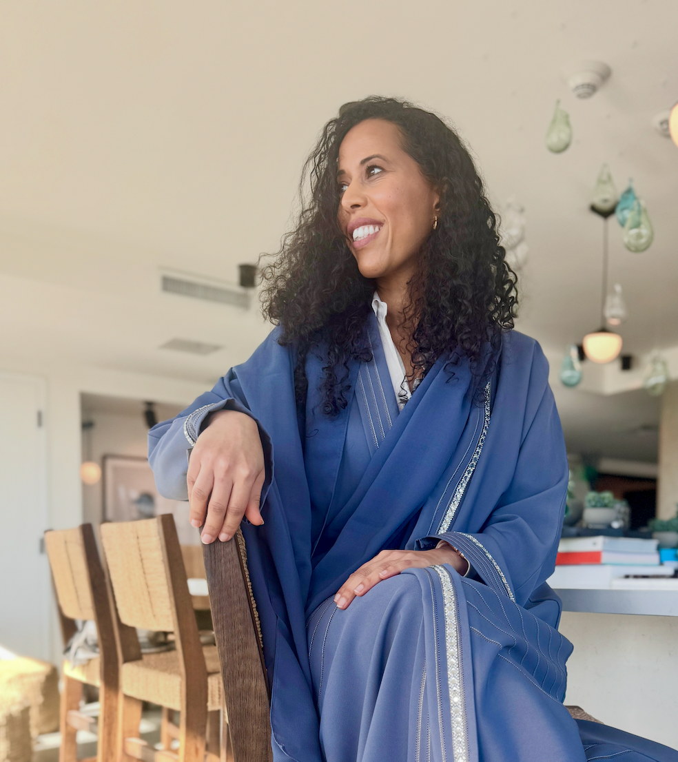 A woman in a blue dress is sitting on a chair