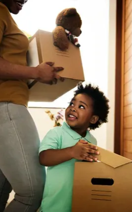A woman is holding a cardboard box and a child is holding a teddy bear.