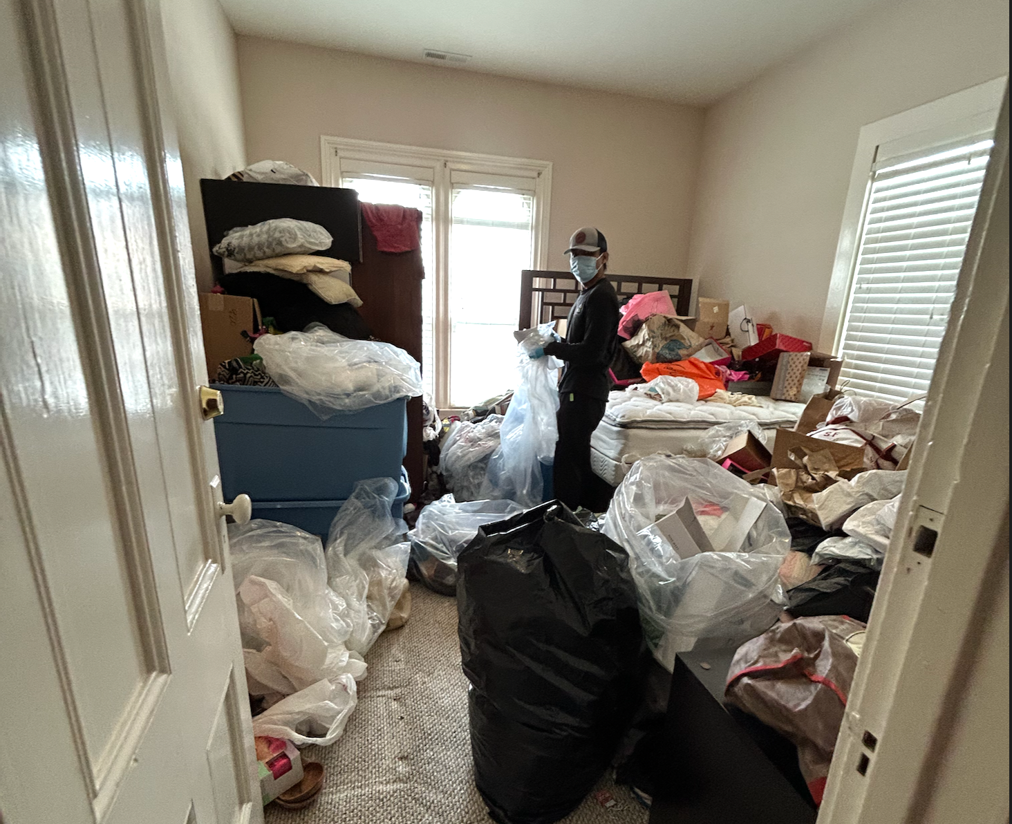 A person sitting in a cluttered room, looking overwhelmed