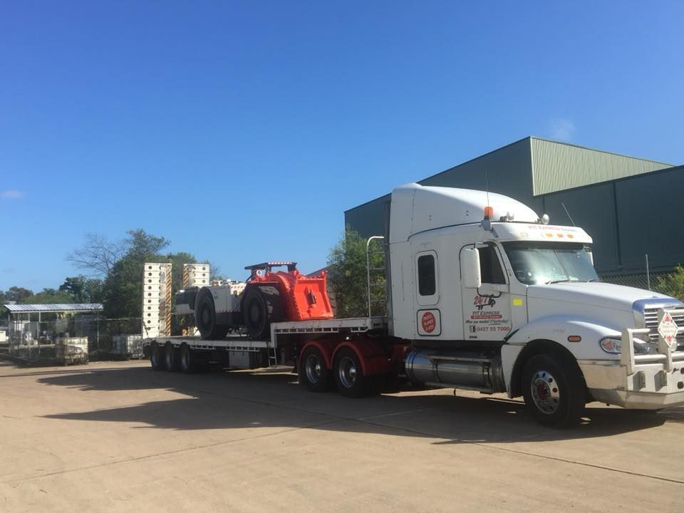 White Semi Truck is Carrying a Red Vehicle on a Flatbed Trailer — Pit Express in Muswellbrook, NSW