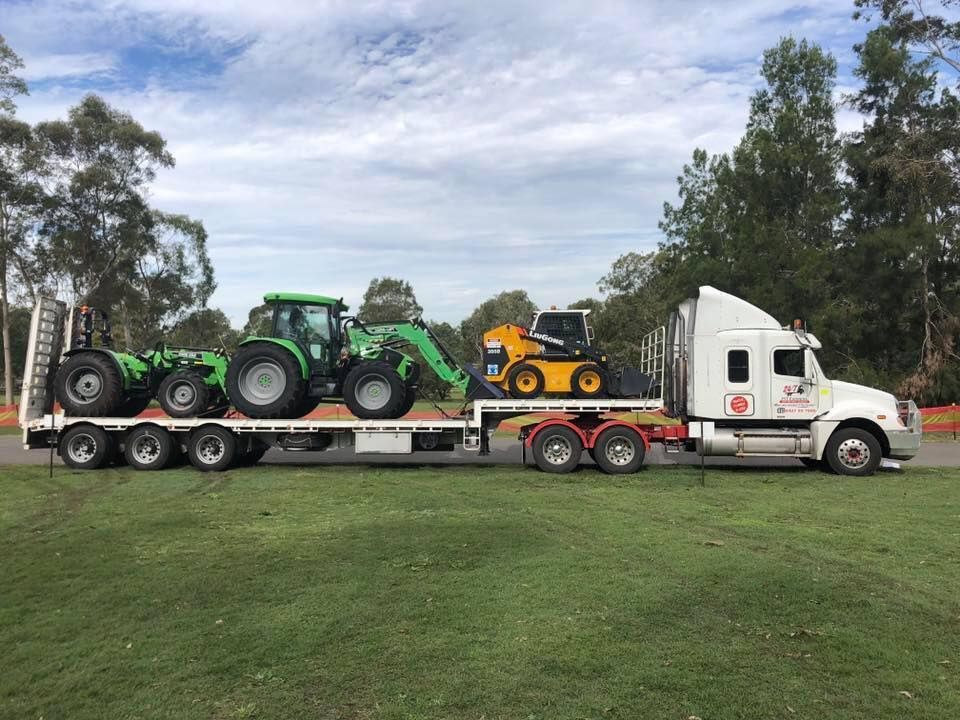 Semi Truck is Carrying Two Tractors on a Flatbed Trailer — Pit Express in Singleton, NSW