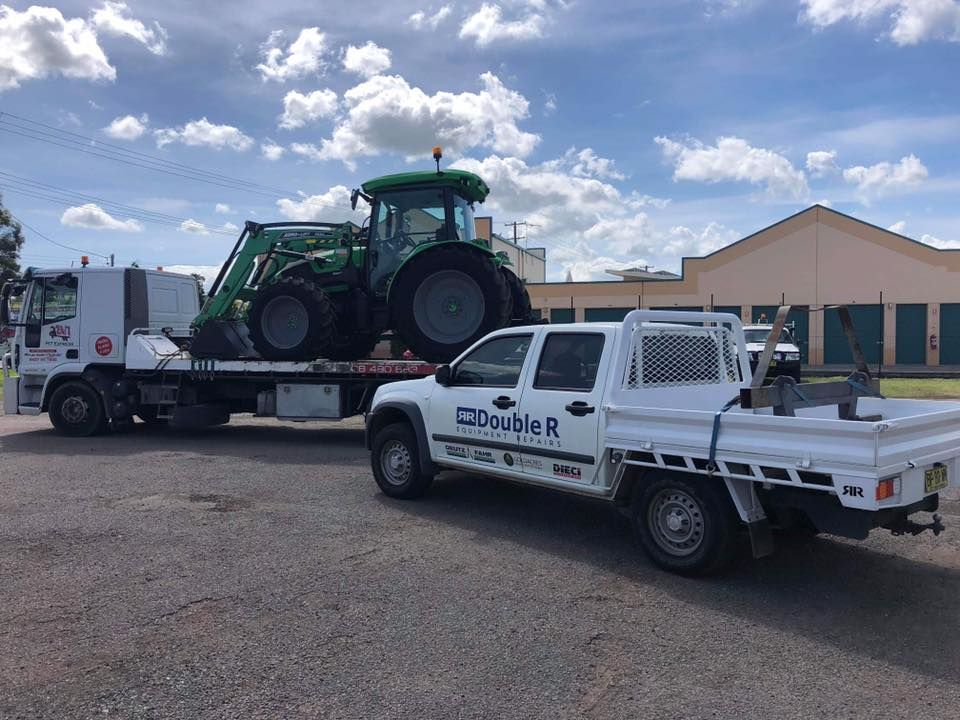 White Truck is Towing a Green Tractor on a Flatbed Trailer — Pit Express in Gold Coast, QLD