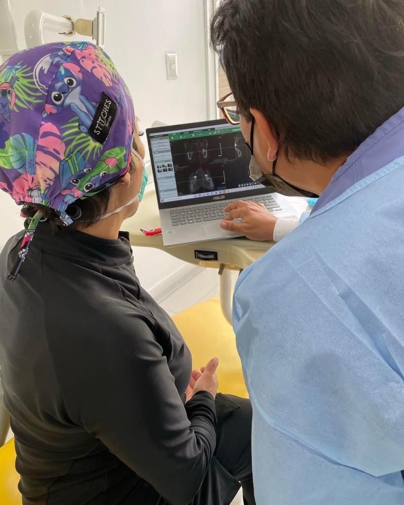 Un dentista y un paciente están mirando una computadora portátil.