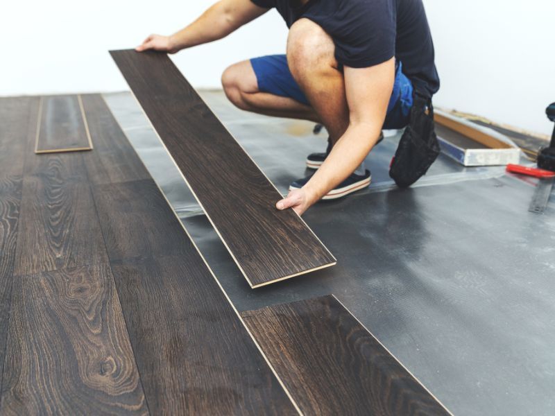 Installer laying dark laminate flooring panels – Gulf of America Flooring, Spring Hill Florida.