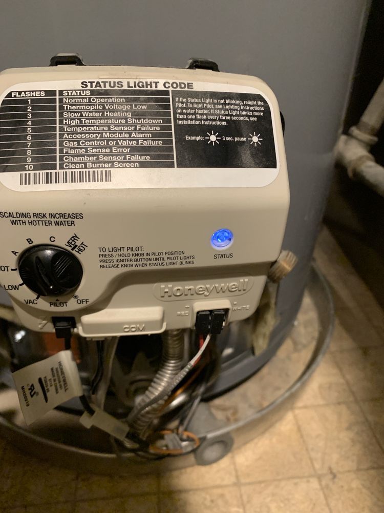 A Honeywell water heater control valve with a blue status light illuminated above a dial set to